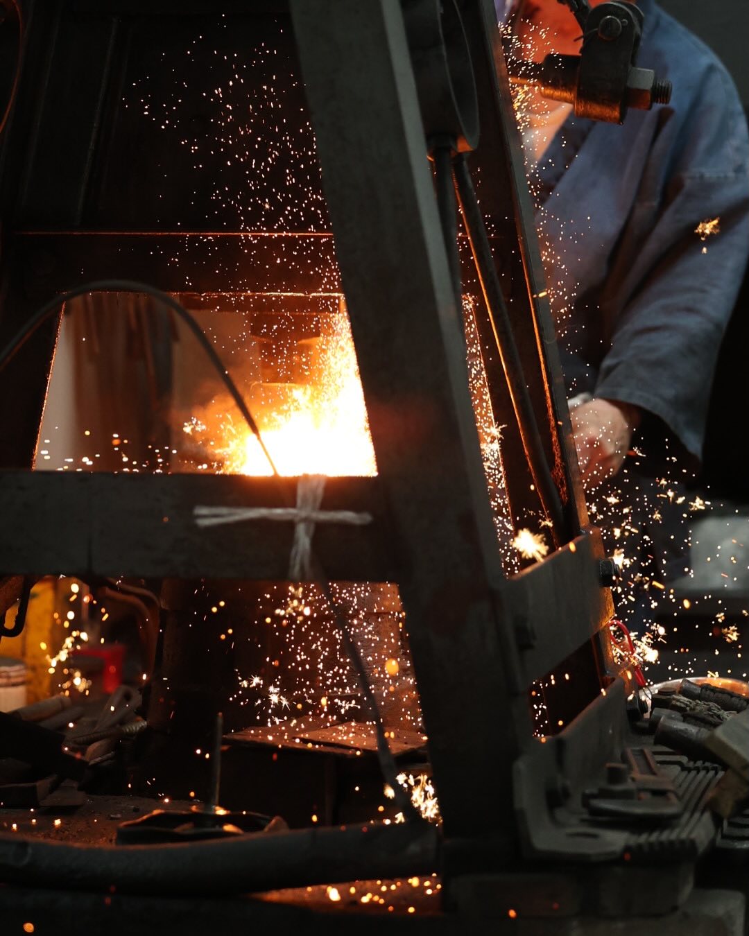 A swordsmith at the forge, sparks flying from the fire